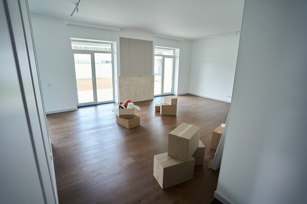 Empty comfortable townhouse room with cardboard boxes on floor during moving